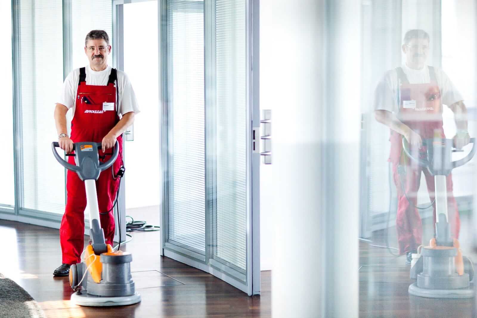 Bei der Gebäudereinigung poliert die Reinigungskraft aus Berlin den Boden mit einer Einscheibenmaschine